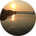 Sunset over tranquil beach, reflecting on calm water, with gentle waves and rocky shoreline. Relaxing seaside view, golden hour scenery.
